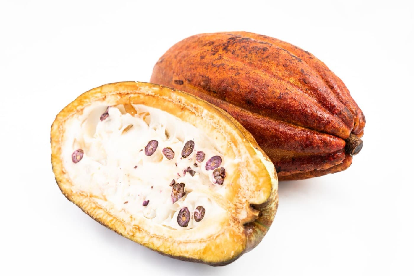 A cocoa pod split open showing white pulp and beans, beside a whole pod